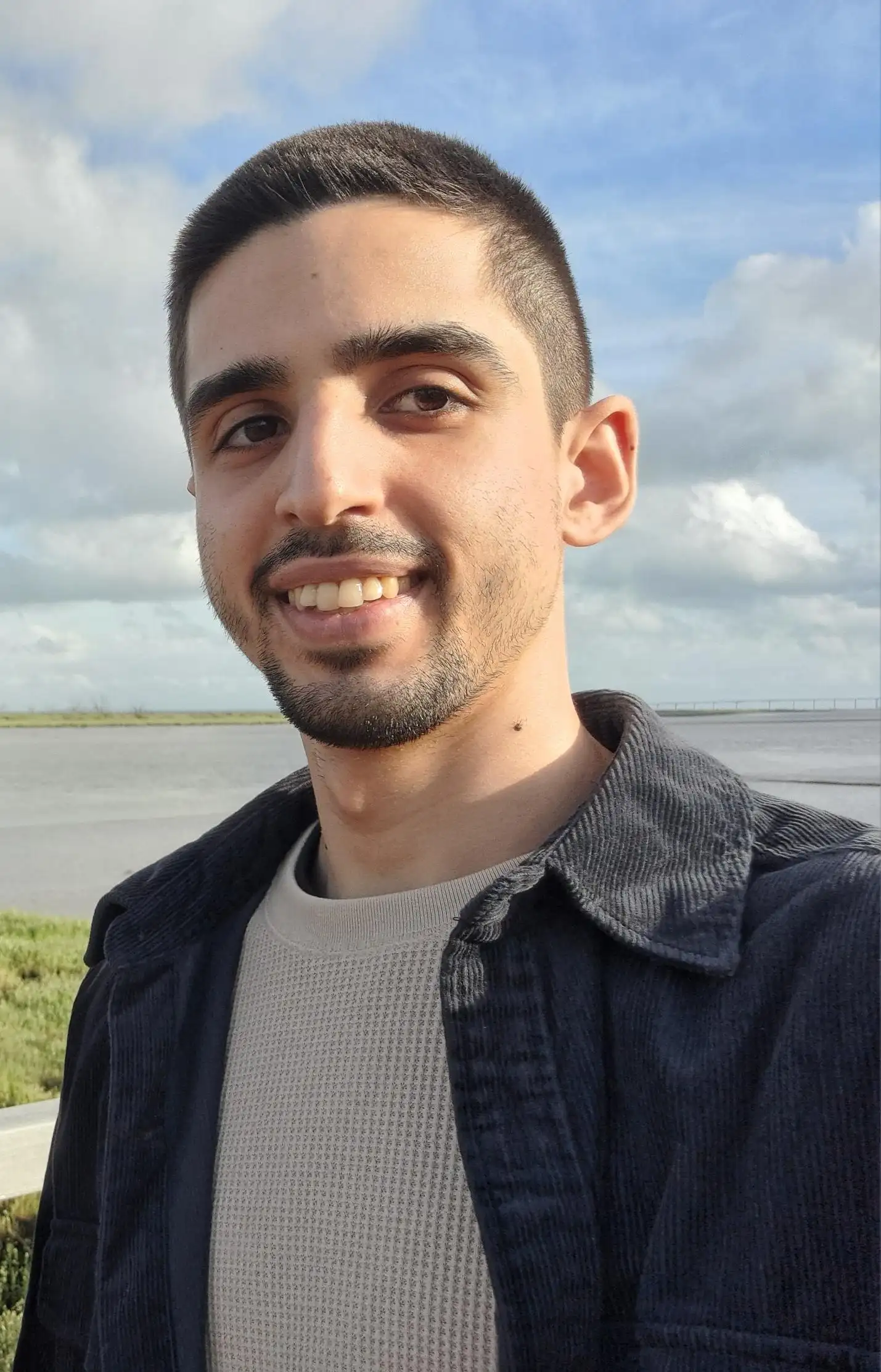 Miguel Martins, Creative Developer based in Lisbon, Portugal, smiling in a red plaid shirt and tortoise shell glasses